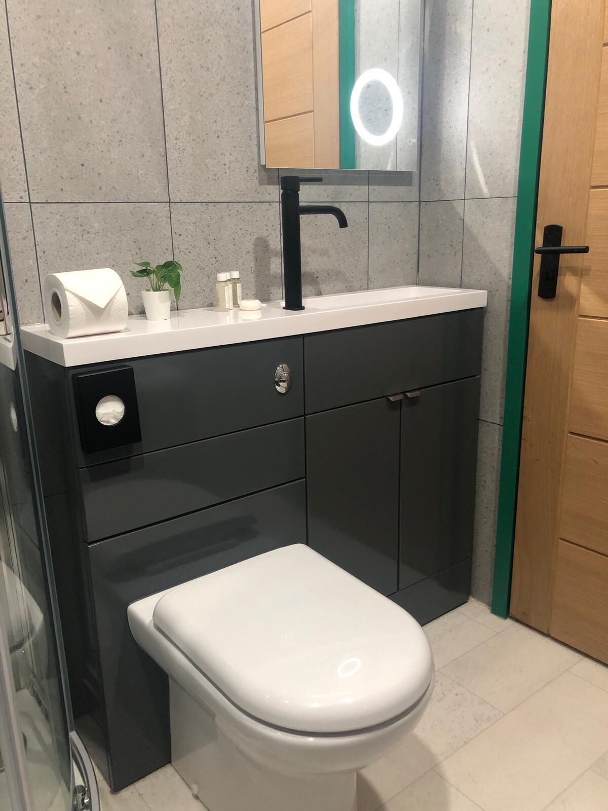 A modern bathroom with a white toilet, a black sink, and a mirror above it.
