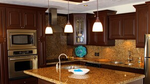 A kitchen with granite countertops, stainless steel appliances, and wooden cabinets. - Sonoran Sky 1107 Spacious Deluxe Best Ocean View Condo (Puerto Peñasco)