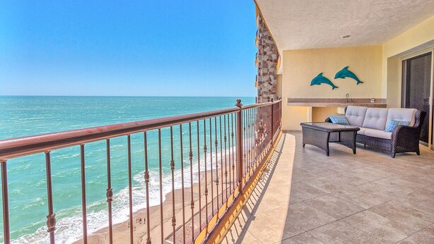 A balcony with a view of the ocean, a sofa, and two dolphin wall art pieces. - Sonoran Sky 1107 Spacious Deluxe Best Ocean View Condo (Puerto Peñasco)