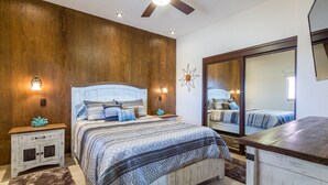 A bedroom with a large bed, wooden walls, a ceiling fan, and a mirror. - Sonoran Sky 1107 Spacious Deluxe Best Ocean View Condo (Puerto Peñasco)