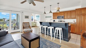 A modern kitchen with a central island, bar stools, and wooden cabinets. - 1415 Butlers Ave. # 12 - Pool - Beach 1 block away (Tybee Island)