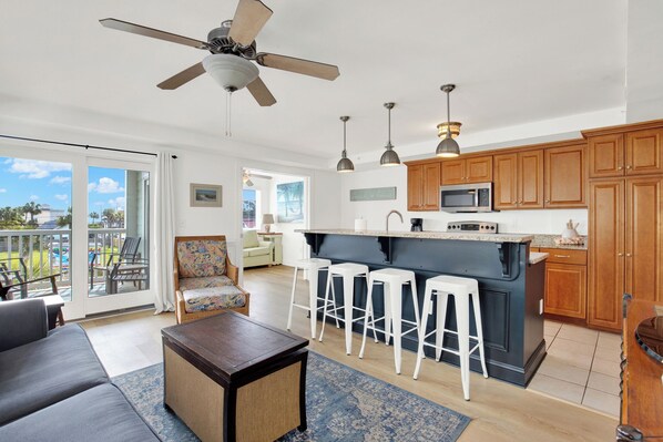 A modern kitchen with a central island, bar stools, and wooden cabinets.