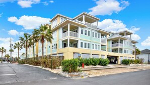 A multi-story hotel with balconies, a parking area, and palm trees. - 1415 Butlers Ave. # 12 - Pool - Beach 1 block away (Tybee Island)