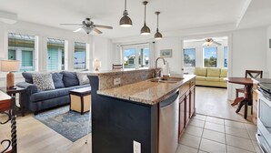 A spacious living area with a large island, a sofa, and a dining table. - 1415 Butlers Ave. # 12 - Pool - Beach 1 block away (Tybee Island)