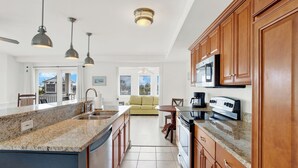 A modern kitchen with granite countertops, wooden cabinets, and stainless steel appliances. - 1415 Butlers Ave. # 12 - Pool - Beach 1 block away (Tybee Island)