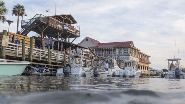 A waterfront dock with several boats, a wooden pier, and a building with a red roof. - Coastal Farmhouse Comfort (Mt Pleasant)