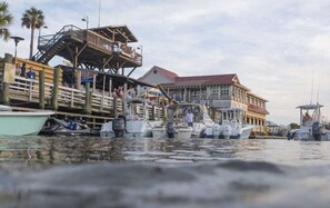 A waterfront dock with several boats, a wooden pier, and a building with a red roof.
