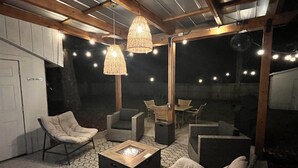 An outdoor patio area with seating, a fire pit, and string lights. - Coastal Farmhouse Comfort (Mt Pleasant)