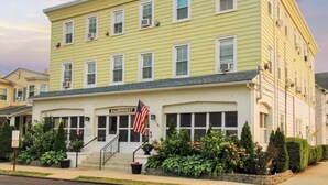 A yellow building with a sign reading "ALLEHUNNYST" and an American flag. - Studio w/ Kitchenette 2 Blocks to Beach & Main Ave | Near Asbury Boardwalk (Ocean Grove)