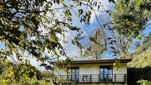 Une maison à deux étages avec un balcon, une porte d’entrée et un petit jardin.