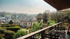 Un balcon donnant sur une maison et la végétation environnante.