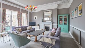 A living room with a sofa, two armchairs, a coffee table, a fireplace, a television, and a bookshelf. - The Zetland Apartment (Saltburn-by-the-Sea)