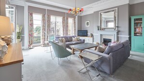 A living room with a sofa, coffee table, and a television. There is a fireplace and a bookshelf. - The Zetland Apartment (Saltburn-by-the-Sea)