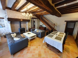 Una sala de estar acogedora con chimenea, un sofá, una mesa de comedor y una escalera.