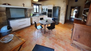 Una cocina rústica con una mesa de comedor, sillas y una lámpara colgante.