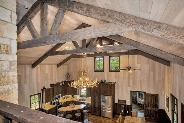 A rustic kitchen with exposed wooden beams, a chandelier, and a large island with seating.