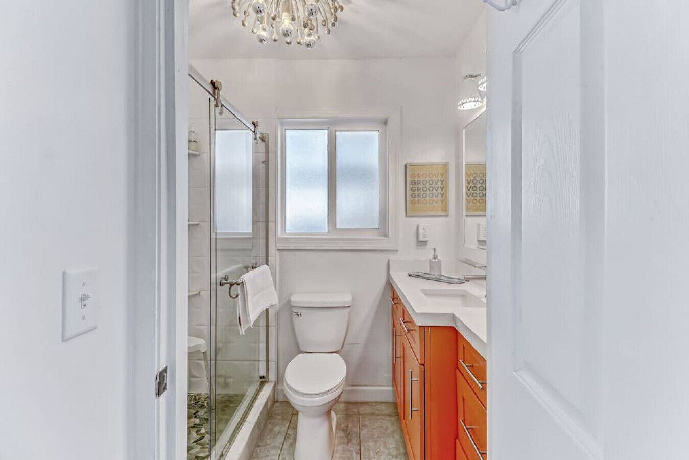 Une salle de bain avec une douche à parois de verre, des toilettes et un meuble-lavabo avec un miroir.