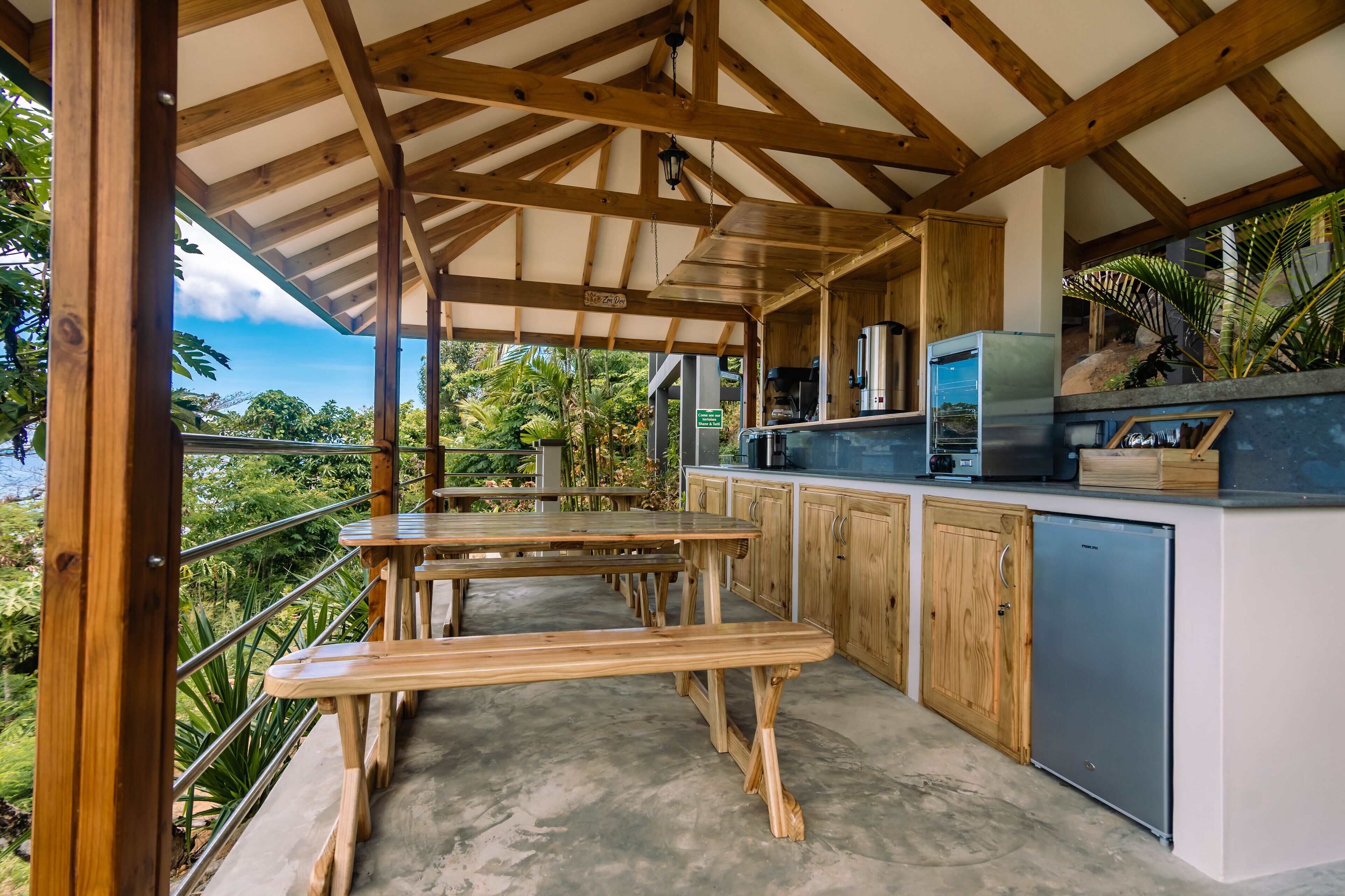 Une cuisine extérieure avec des tables en bois et une vue sur l’océan.