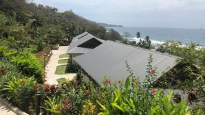 A coastal property with a large house, lush gardens, and a view of the ocean.