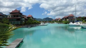 A marina with several boats docked, surrounded by buildings with red roofs and a clear blue sky.
