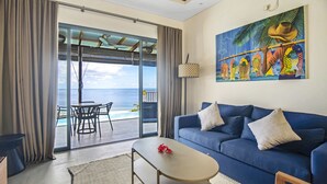 A living room with a blue sofa, a coffee table, and a painting of a person with fish.