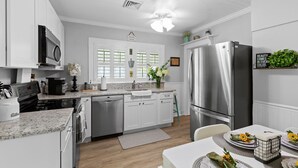 A modern kitchen with stainless steel appliances, white cabinetry, and a central island. - Genevieve's Cottage! Totally Renovated with all the Charm! (Hixson)