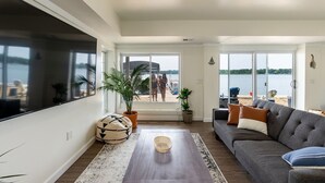Een ruime woonkamer met een groot raam, een bank en uitzicht op het strand.
