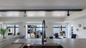 Een moderne keuken met een roestvrijstalen spoelbak, grote ramen en uitzicht op de omgeving.
