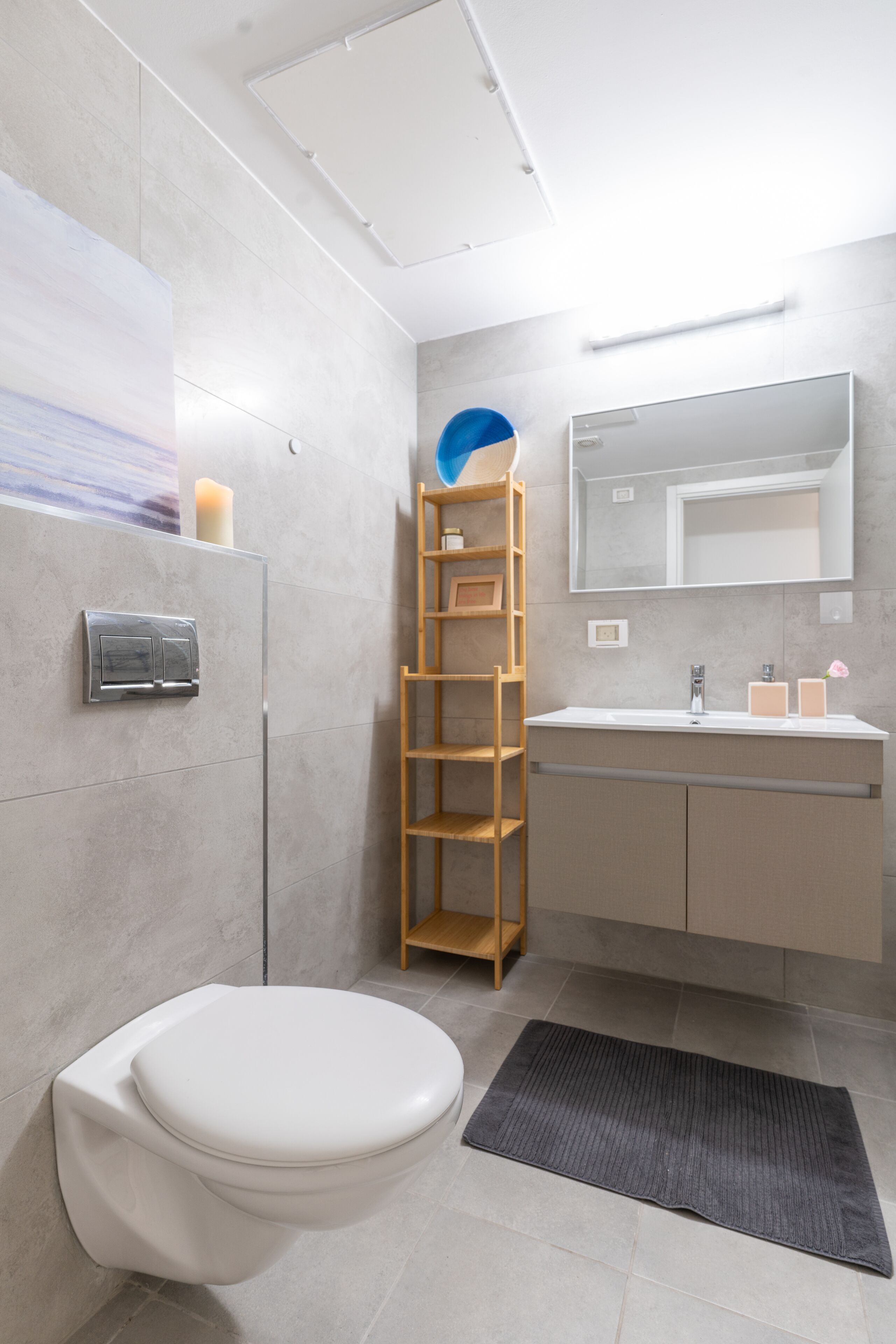 A modern bathroom with a toilet, sink, and mirror.