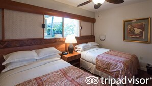 Une chambre d’hôtel avec deux lits, un ventilateur de plafond, une fenêtre donnant sur un beau paysage, une lampe et un tableau encadré au mur.