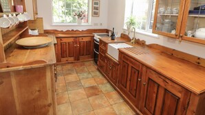 Une cuisine avec des meubles de rangement en bois, un évier et une fenêtre donnant sur un paysage verdoyant.
