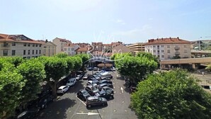 Ein Parkplatz mit Autos, Bäumen und Gebäuden im Hintergrund.