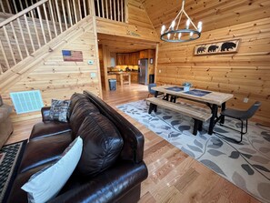 A wooden interior with a leather sofa, a dining table with benches, and a staircase. - GORGEOUS LAKE FRONT CABIN - PRIVATE LAKE ACCESS-FISHING, KAYAKING, AND HIKING. (Topton)