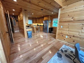 A wooden cabin interior with a kitchen, dining area, and a small bathroom.
