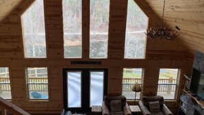 Una cabaña con ventanas amplias, una chimenea y un cartel que dice 'Welcome to the Lake'.