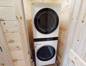 A compact, white LG wall-mounted washer and dryer unit in a wooden-paneled room.