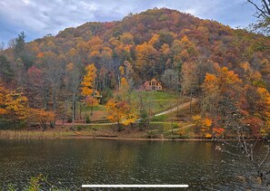A cabin on a hill surrounded by autumn foliage.