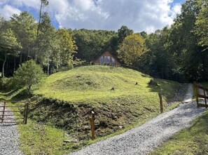 A house on a grassy hill with a gravel path leading to it.