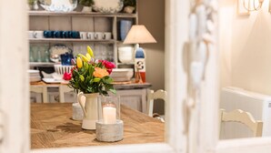 A dining table with a vase of flowers and a candle, surrounded by chairs.