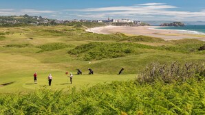 A golf course with a beach and ocean in the background.