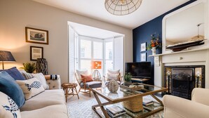 A living room with a sofa, armchair, coffee table, fireplace, television, and a large window.