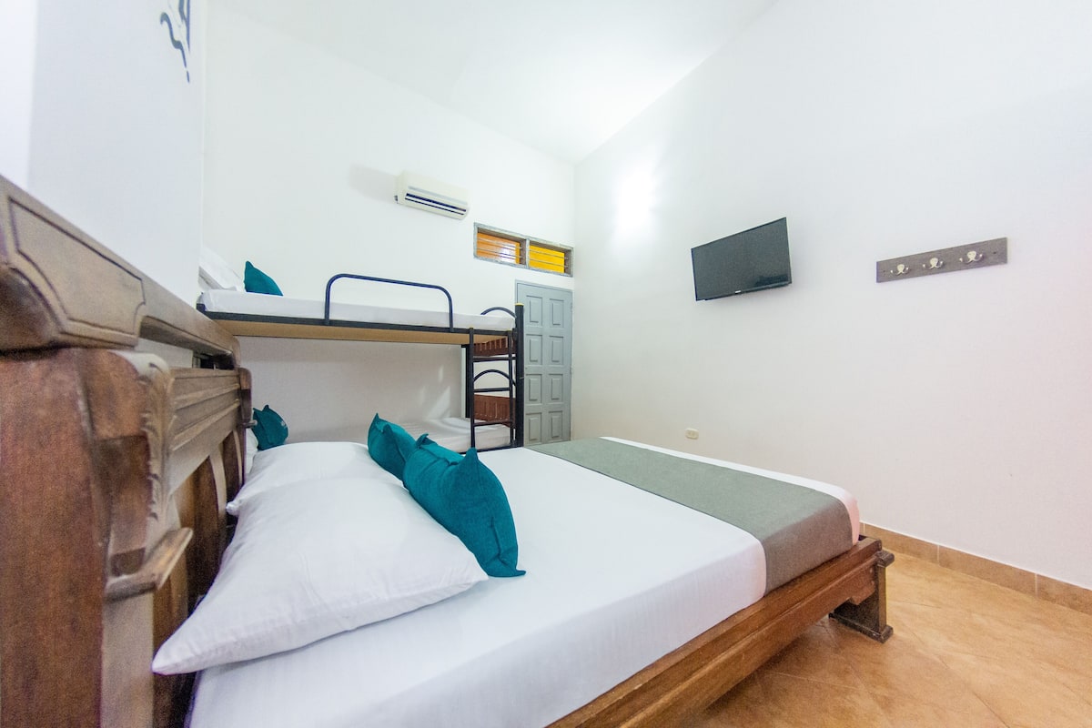 A room with bunk beds, a desk, and a television on the wall.