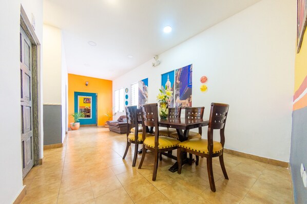 Comedor con mesa y sillas de madera, una planta en maceta y una pared decorada con cuadros.