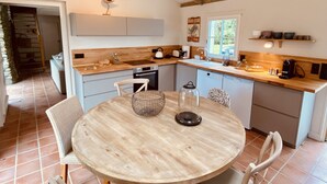 A modern kitchen with wooden beams, a round table, and a dining area.