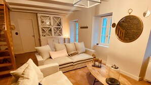 Un vaste espace de vie comprenant un grand canapé, une table basse et un escalier menant à un niveau supérieur.