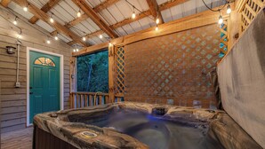 Uma banheira de hidromassagem com exterior de madeira, um deck de madeira e uma porta verde.