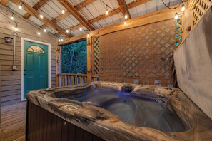 Ein Whirlpool mit HolzauĂenverkleidung, einer Holzterrasse und einer grĂŒnen TĂŒr.