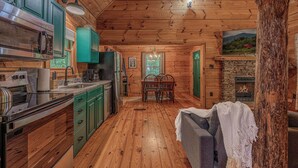 Interior de uma cabana de madeira com cozinha, sala de jantar e lareira.
