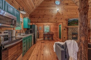 Ein Holzblockhaus-Interieur mit KĂŒche, Essbereich und Kamin.