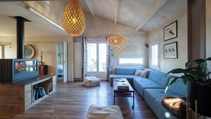 Un salon moderne avec une cheminée, un canapé, une table basse et un luminaire suspendu.